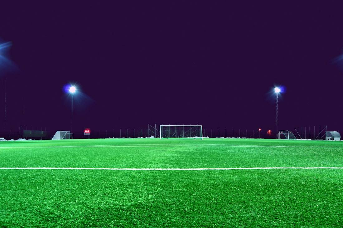 A green soccer field illuminated by bright stadium lights at night
