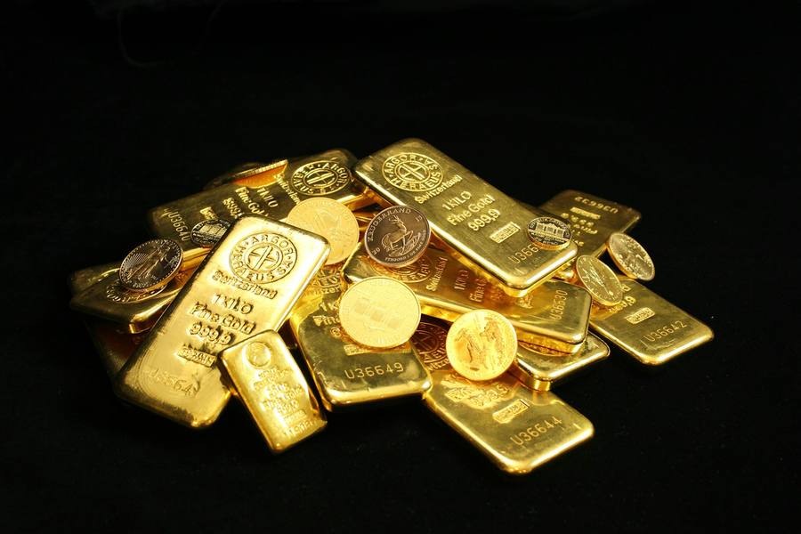 A pile of gold bars and coins on a black background